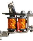 Side profile of a Jonesy-style one-off coil liner tattoo machine by Lucky Supply with orange wrapped coils, hinged tube vice, compact handmade frame, and traditional liner configuration.