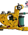 Colorful tattoo machine with speckled yellow design on a white background, featuring Lucky Mfg branding.