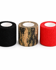 Three rolls of coflex tape on a white background: one black, one camouflage in tan and black, and one bright red.
