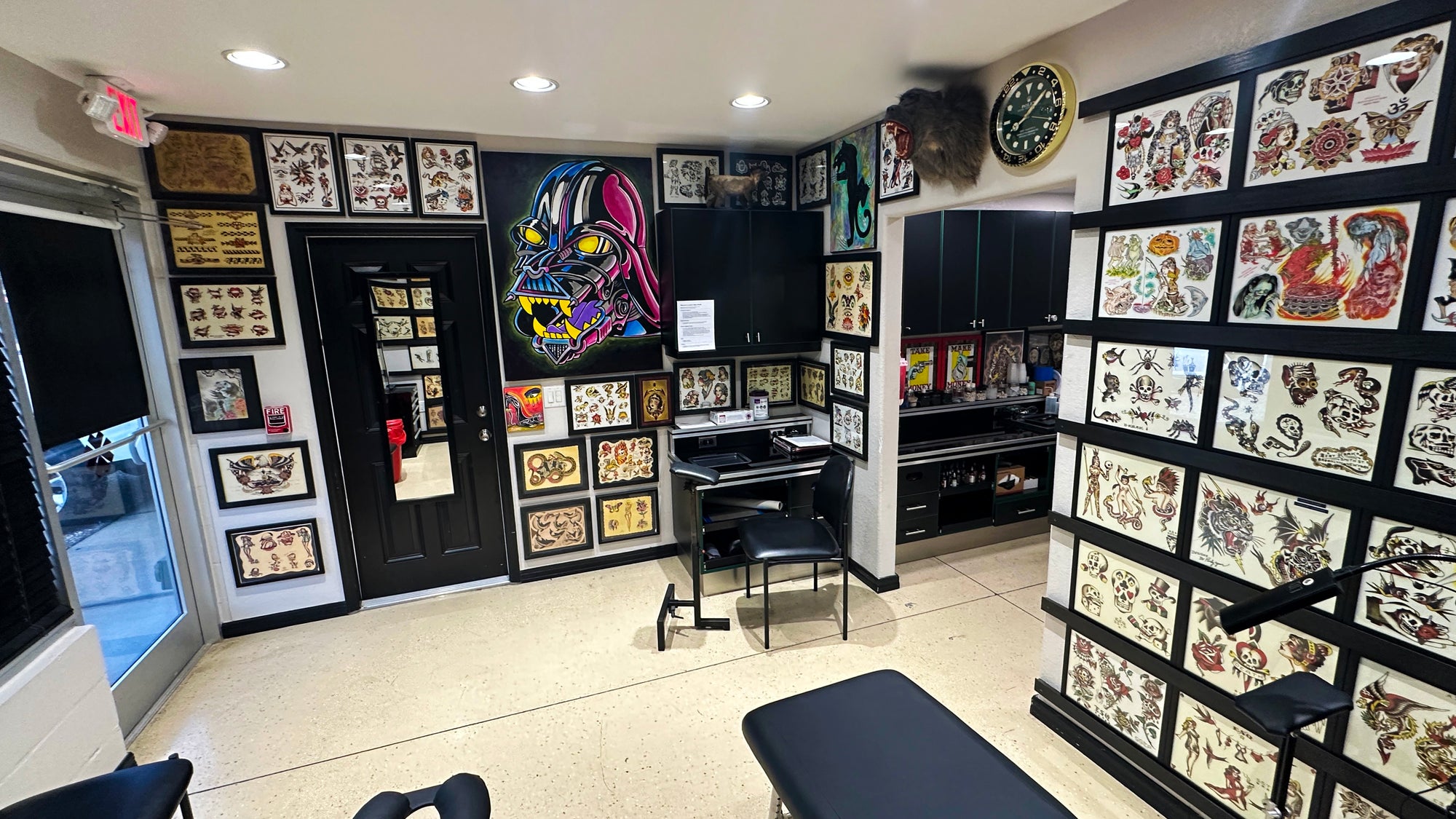 Tattoo studio interior with tattoo designs on walls and a bench.