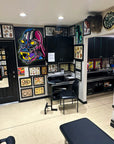 Tattoo studio interior with tattoo designs on walls and a bench.