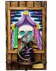 A framed art piece featuring a colorful painting of a skull under purple drapery, with a sculptural rat figurine in the foreground and a small plaque at the bottom reading Mike Wilson and Sam Hambrick.