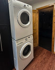 Stacked washer and dryer set against a wooden wall.