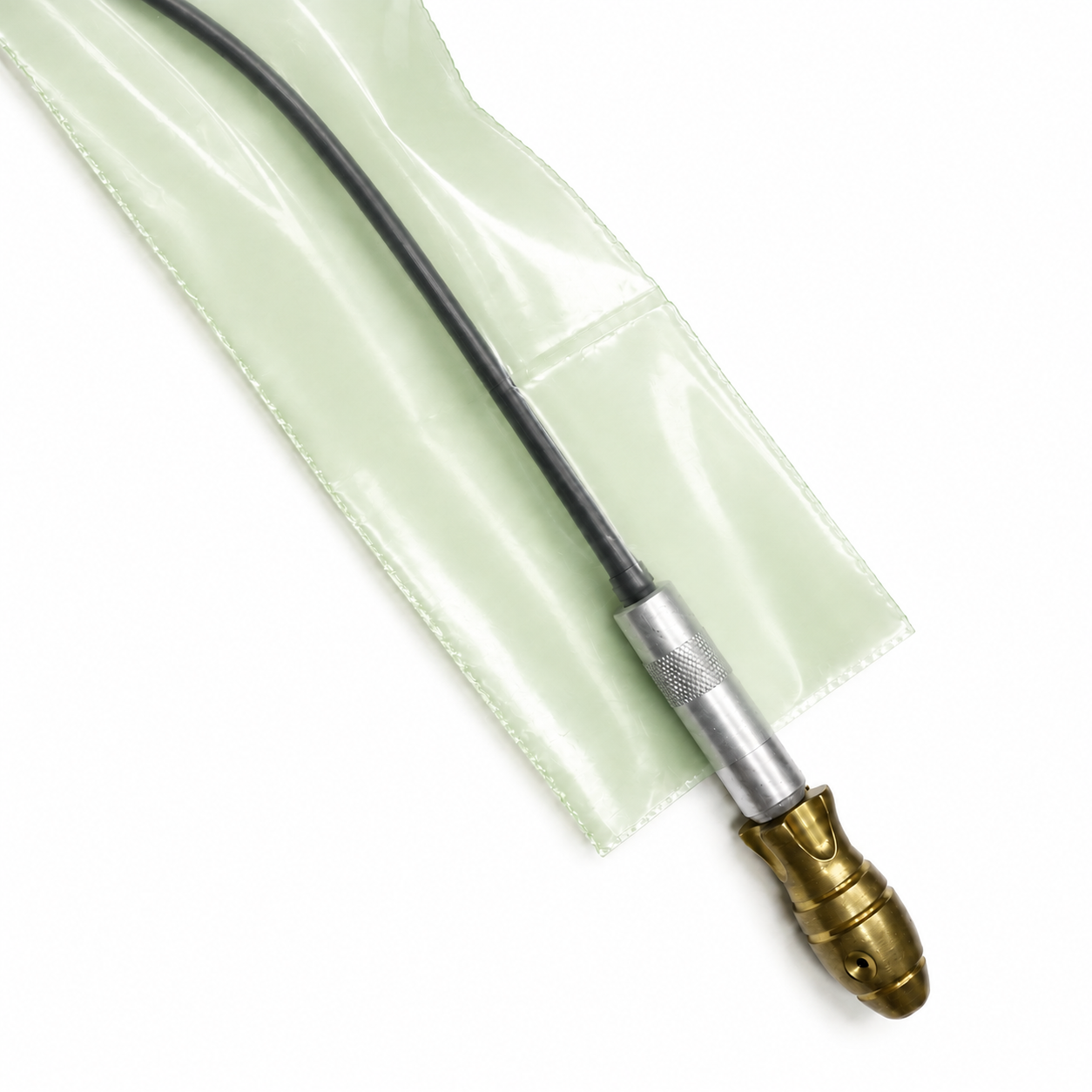 A close-up of a black cable with a brass and silver connector, resting on a translucent pale green protective sleeve against a white background.
