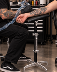 Professional tattoo artist using Lucky Supply Portable Arm Rest while tattooing client