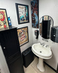Bathroom with a sink, cabinets, and framed artwork on the wall.