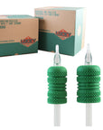 A photo of two disposable tattooing tubes with green grips, alongside their packaging box with branding and product information.